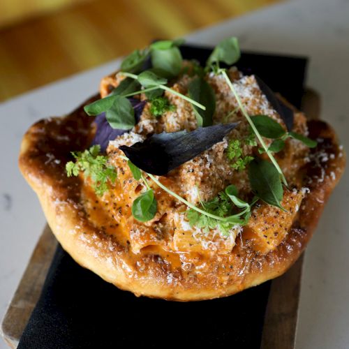 A savory dish featuring a crust topped with pasta in red sauce, herbs, and grated cheese, served on a wooden board.