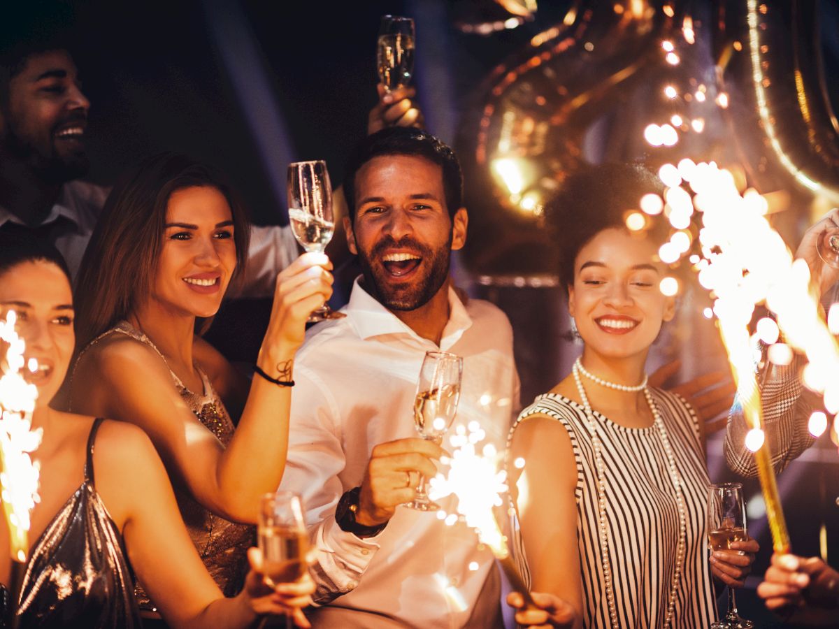 A group of people celebrating with sparklers and champagne, smiling and enjoying a festive atmosphere.