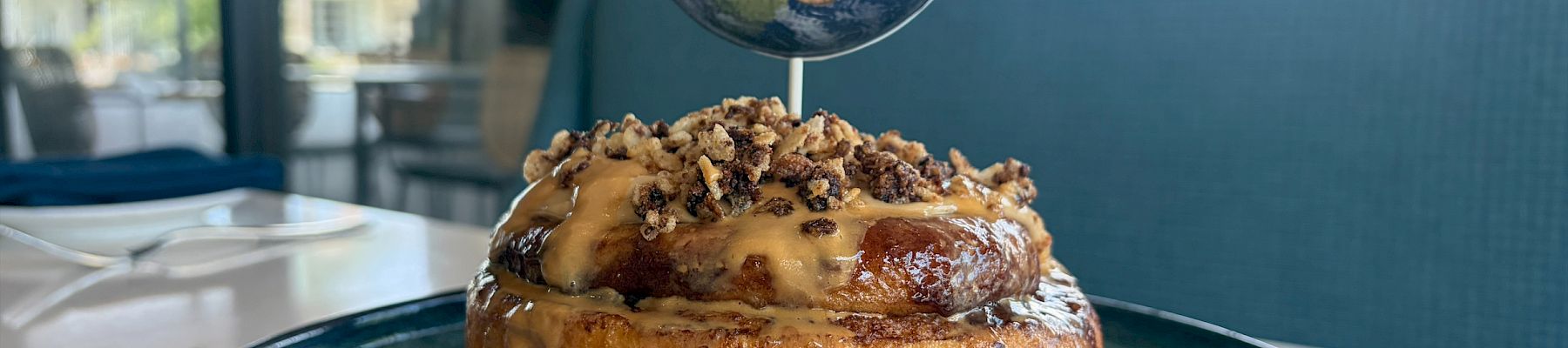 A globe-topped dessert sits on a plate, with caramel sauce drizzled around it in a bright caf&eacute;.
